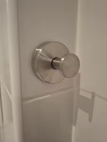 Brushed silver suction hook on a shower panel