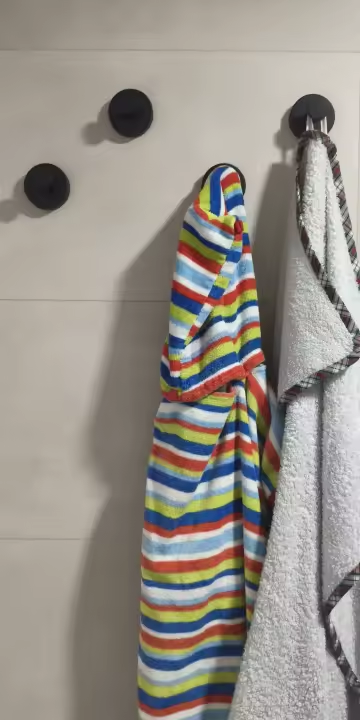 Matte black suction hooks holding a striped hooded towel