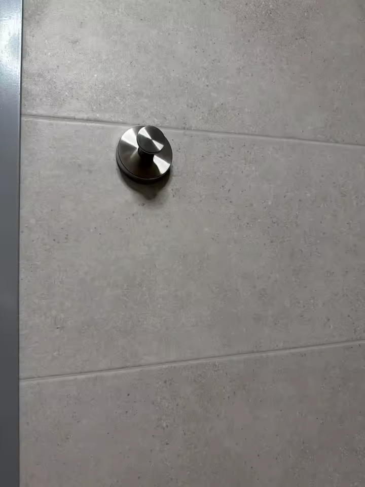 Silver suction hook on a grey tiled wall